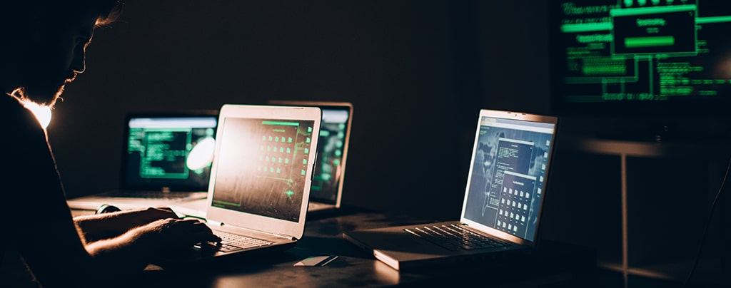 hacker sitting in the dark room infront of his computers, hacking some internet data